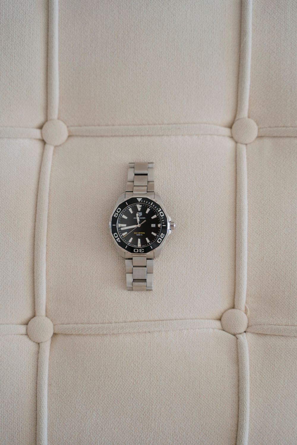 Silver watch displayed on white textured fabric background.