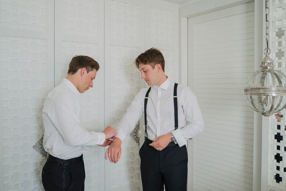 Getting ready scene with formal attire and suspenders in a bright room.