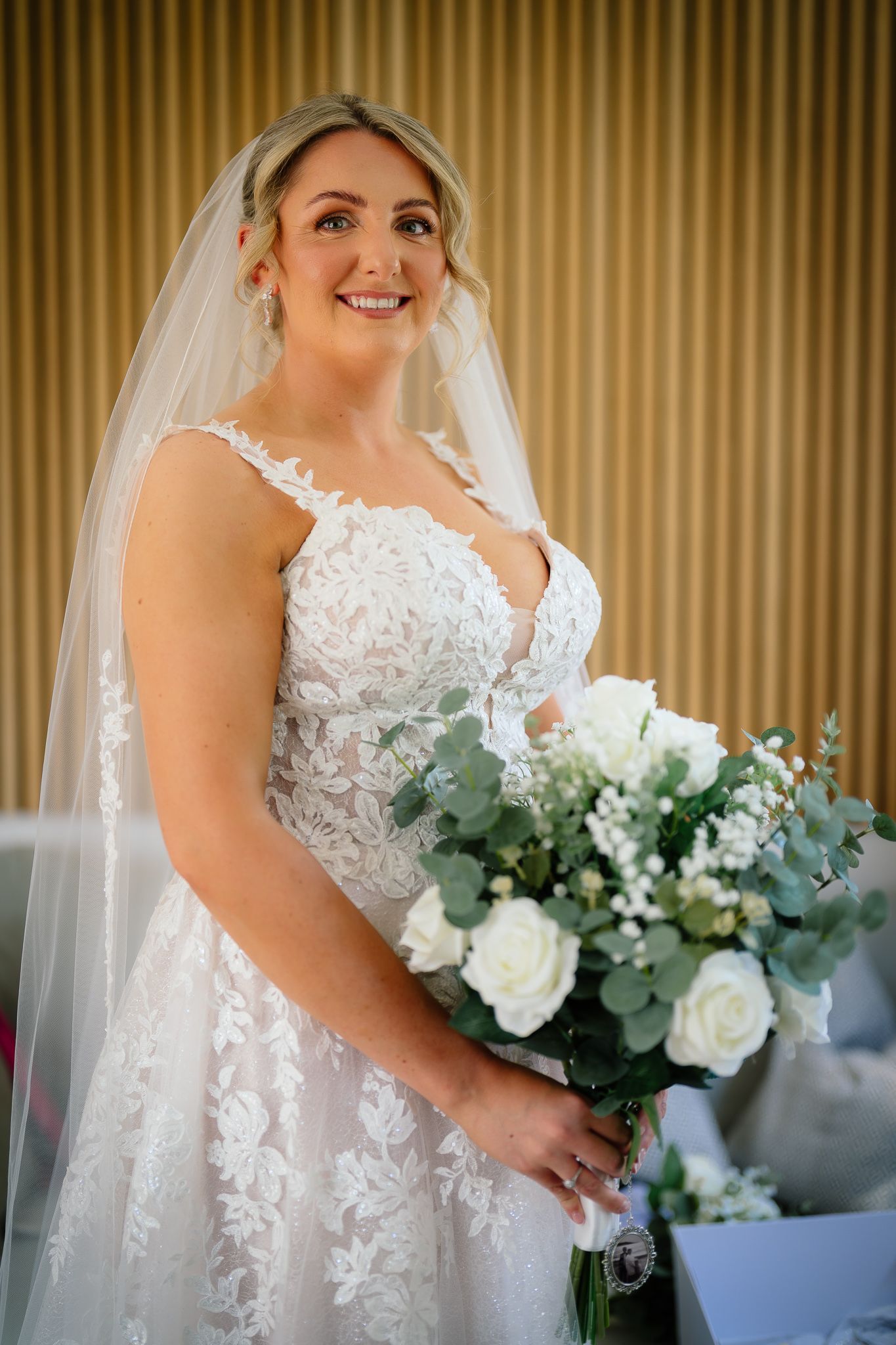 Close-up shots of bride in lace wedding dress holding white and green floral bouquet with eucalyptus.