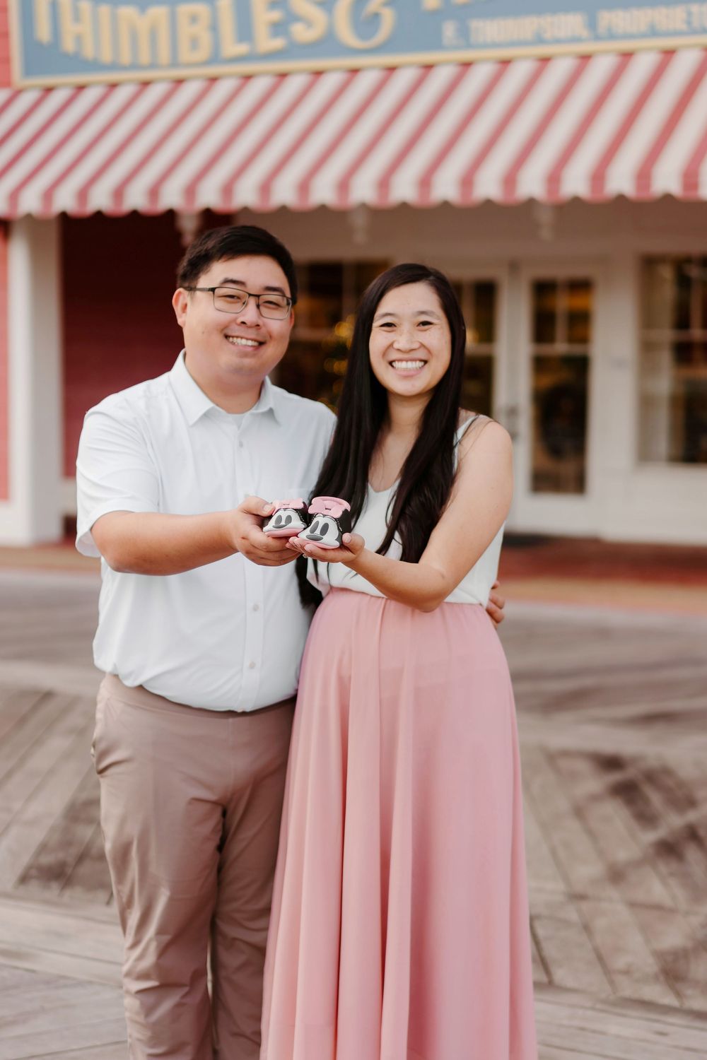Couple in pink dress and white shirt sharing dessert outside a vintage storefront.