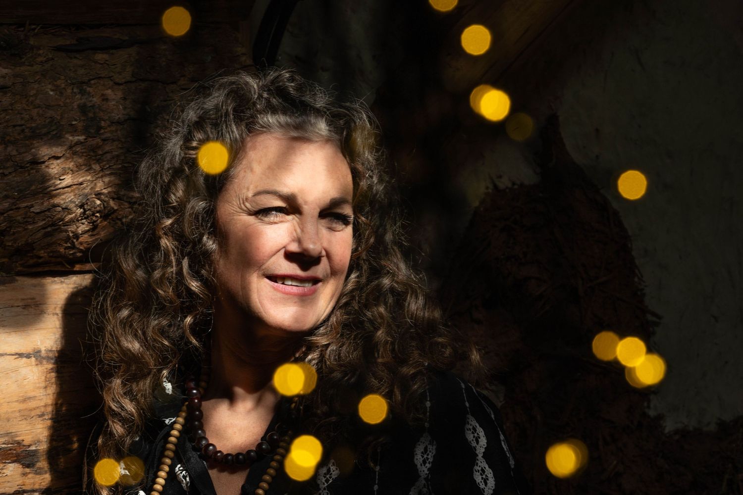 personal branding photography Brighton woman smiles with dark brown hair. the photo has bokeh fairy lights in the image