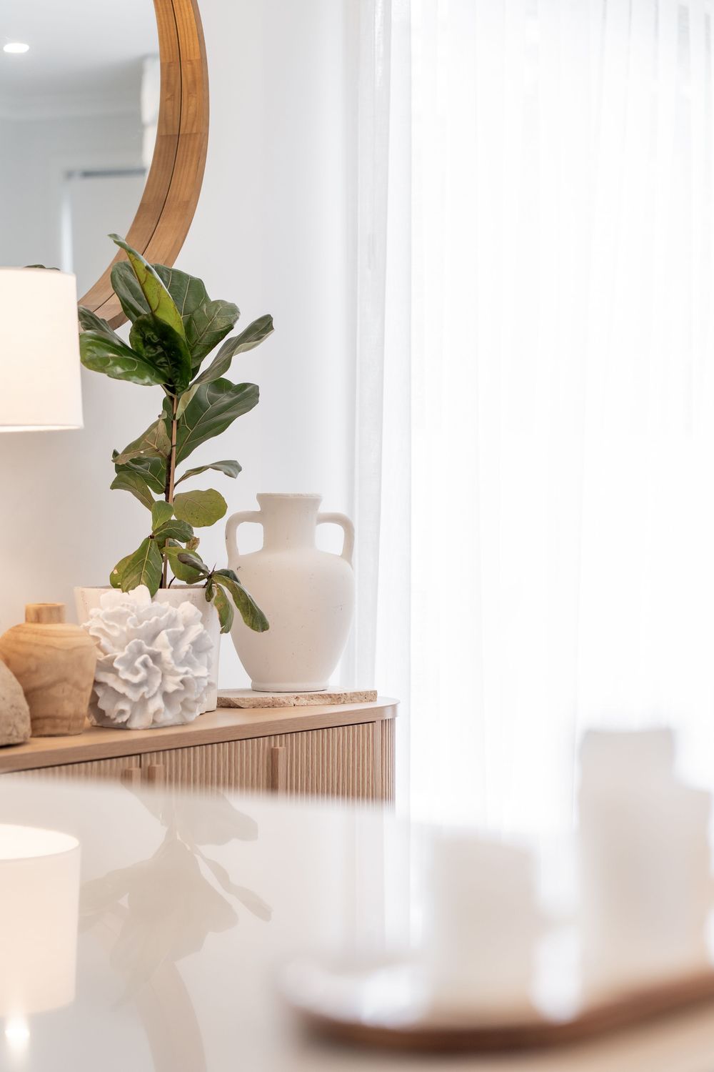 Modern interior design featuring a white table lamp and decorative objects in a bright, minimalist setting.