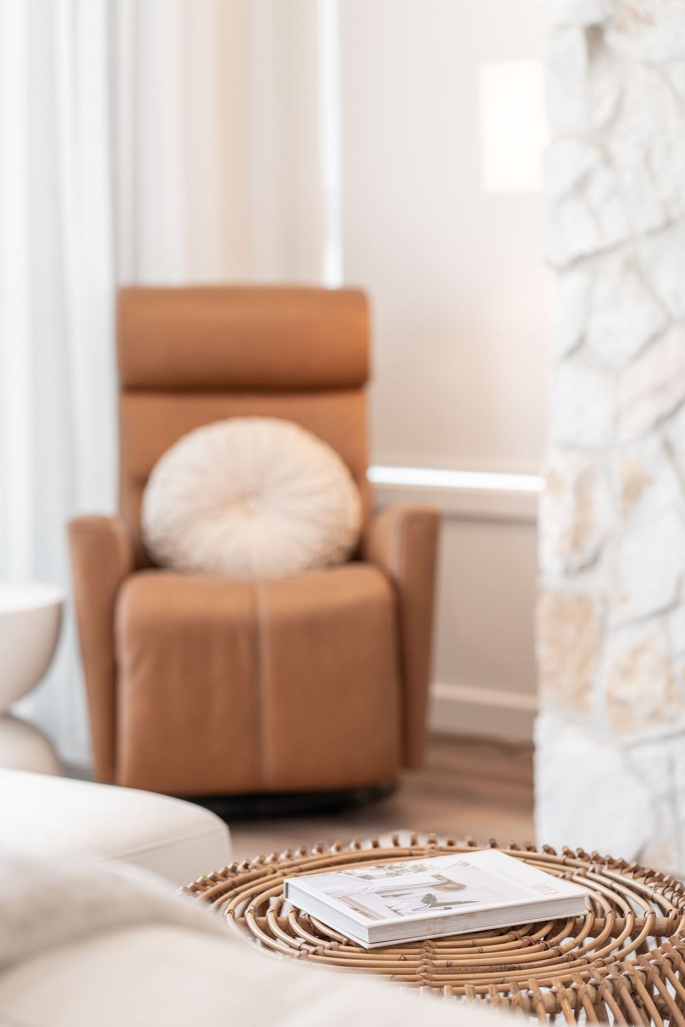 Tan leather armchair with woven rattan decor elements in a bright, contemporary living space.