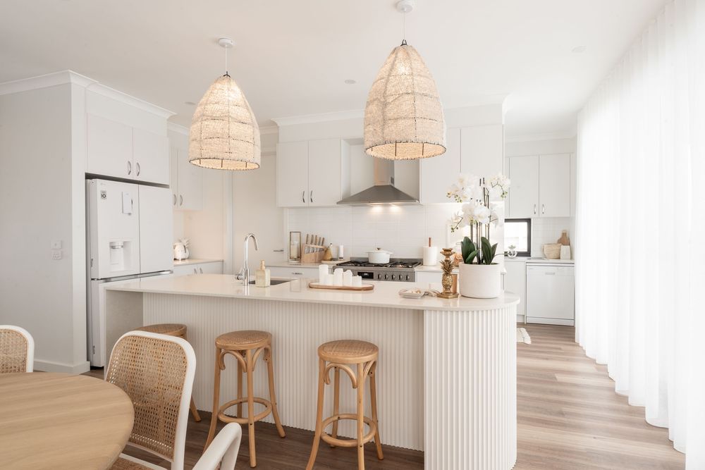Bright coastal-style kitchen with white cabinets, rattan pendant lights, and natural wood accents creating an airy atmosphere.
