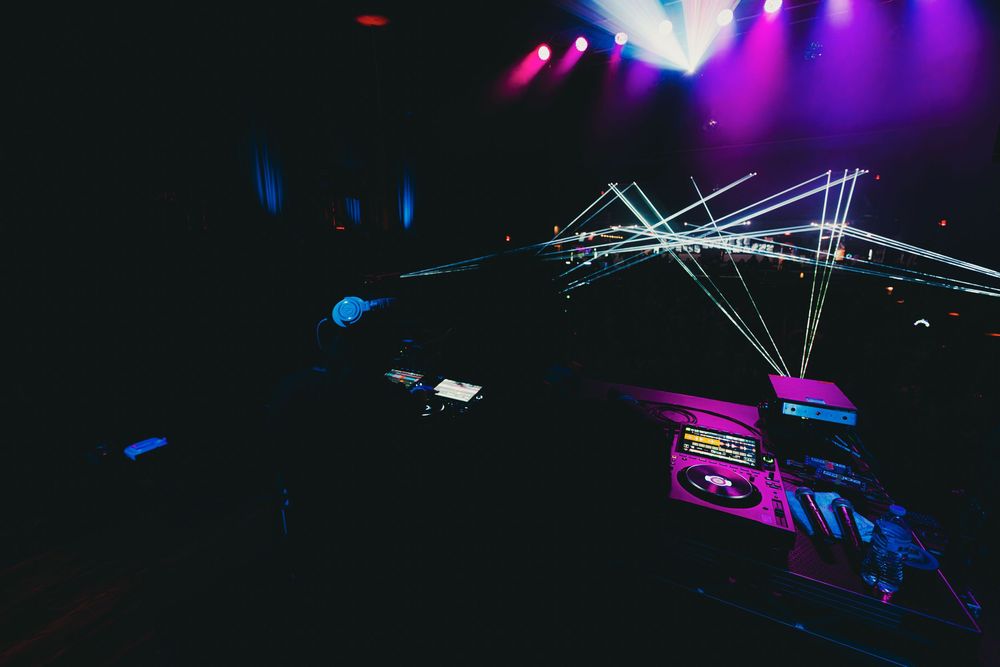 Concert stage illuminated with vibrant purple and blue lighting effects creating a dramatic atmosphere during performance.