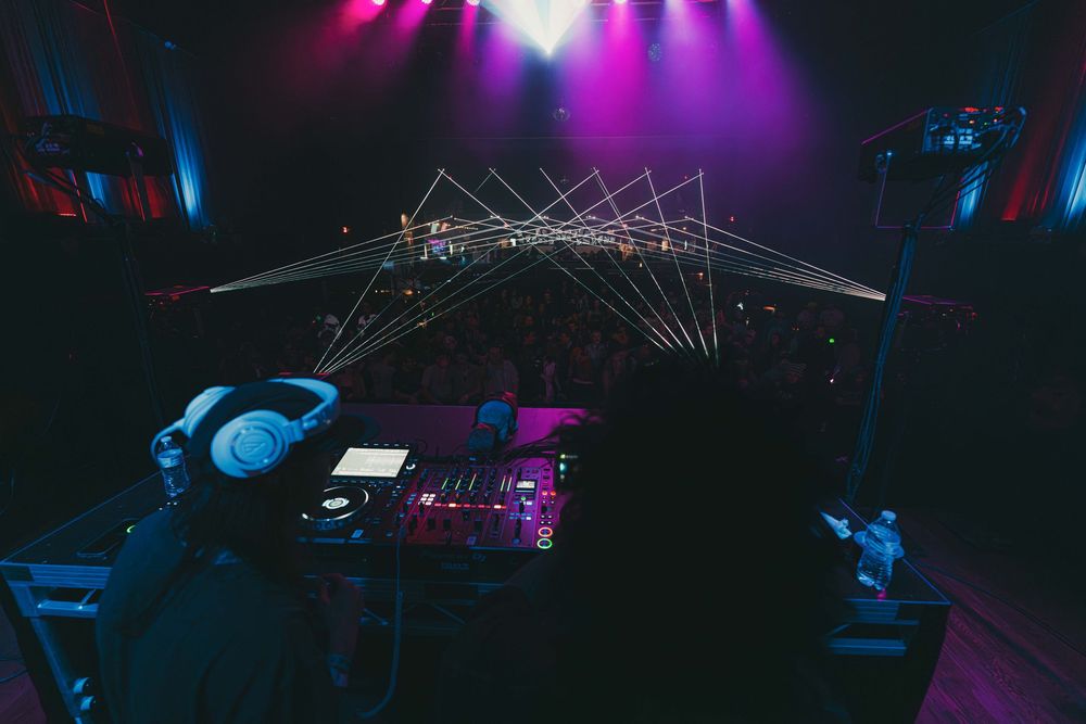 Concert stage illuminated with vibrant purple and blue lighting effects during a live performance.