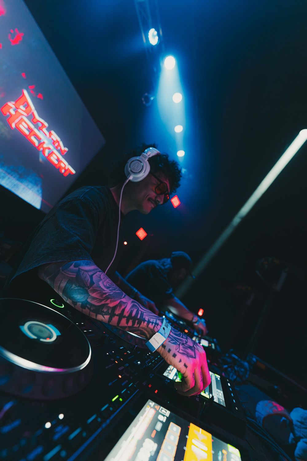 DJ equipment and turntables illuminated by blue stage lights during a nightclub performance.