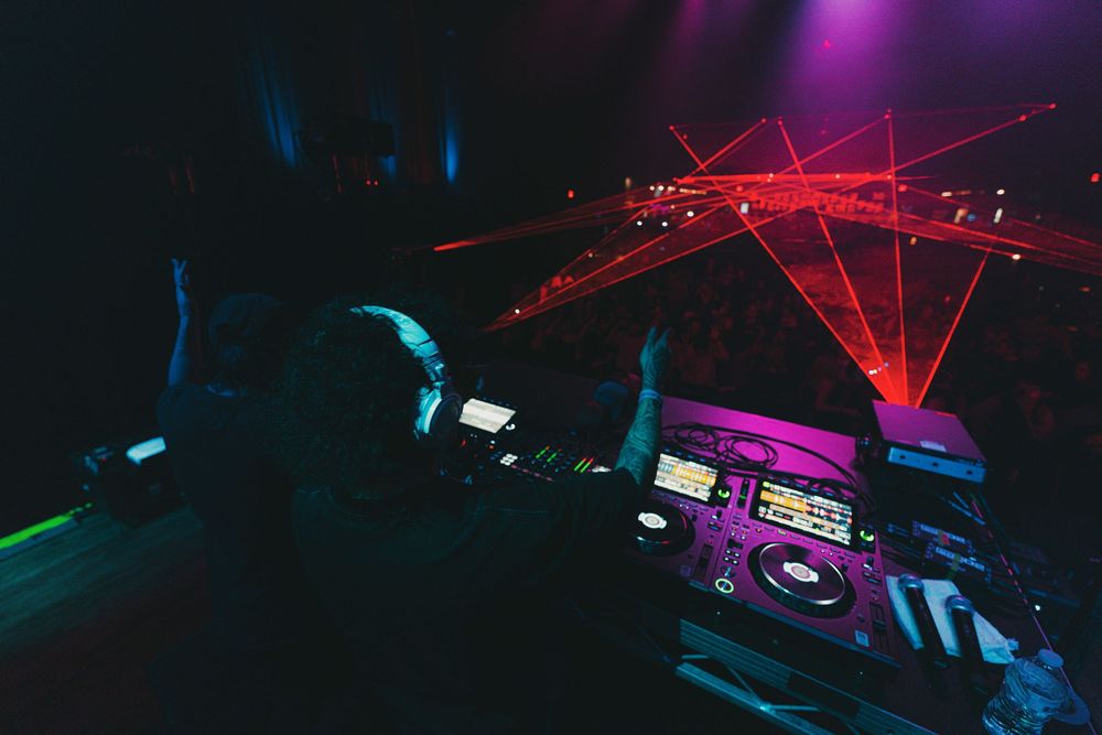 Colorful laser lights and geometric patterns illuminate a dark nightclub ceiling with vibrant purple and blue hues.