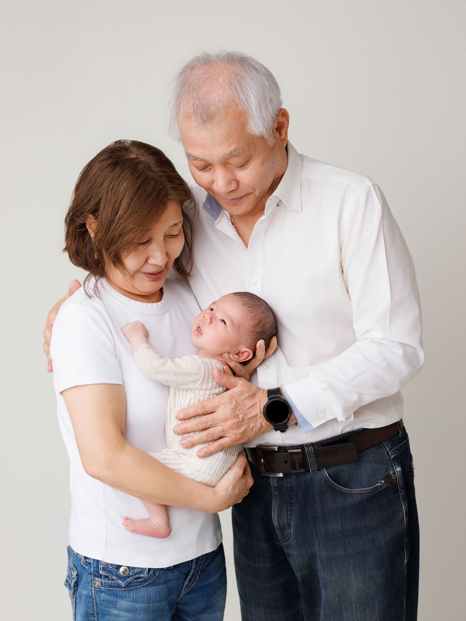 A family in white shirts and jeans shares tender moments with a newborn baby in a series of heartwarming poses.