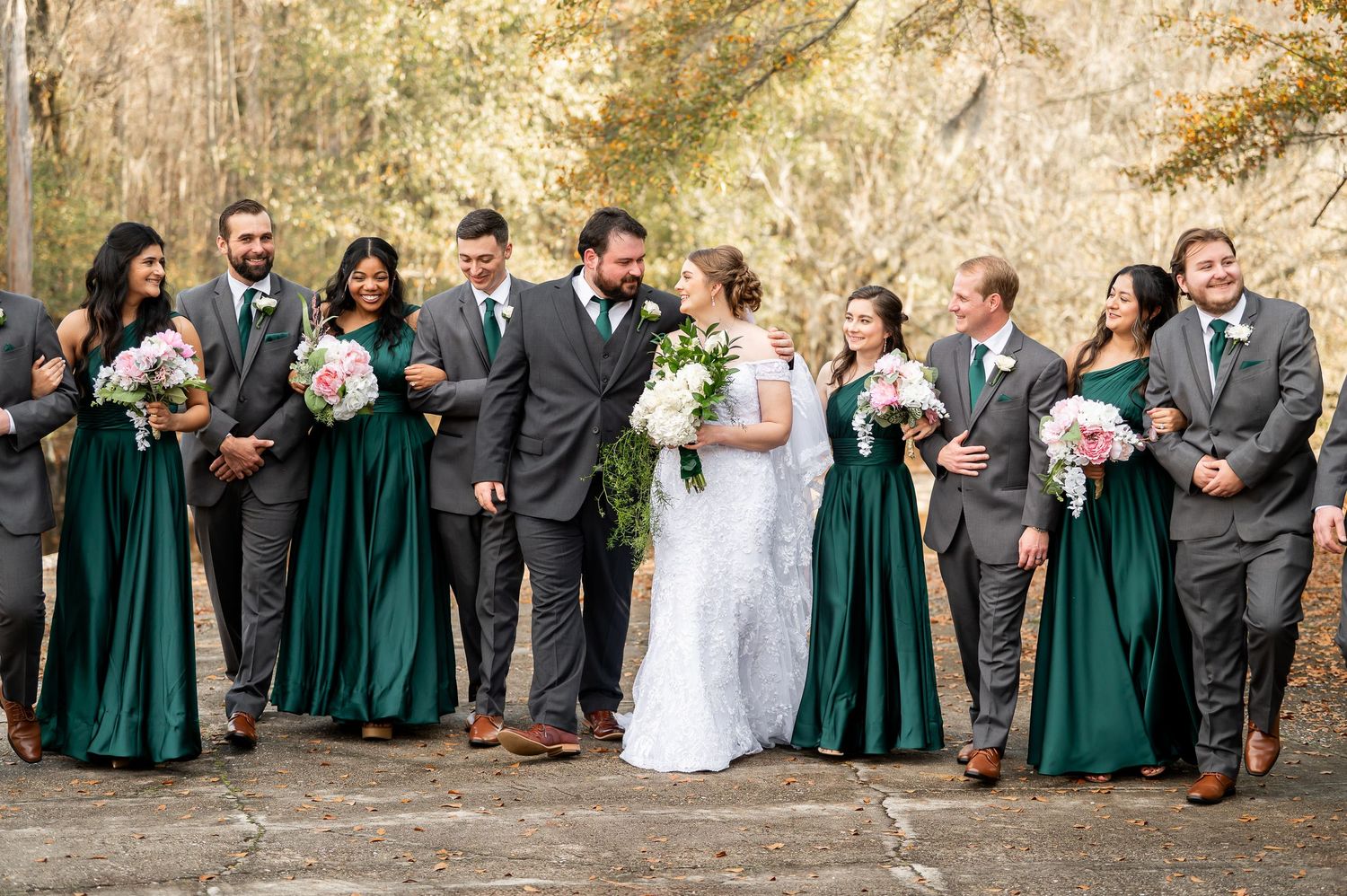 Wedding party members in emerald and gray attire gather for group photos outdoors.