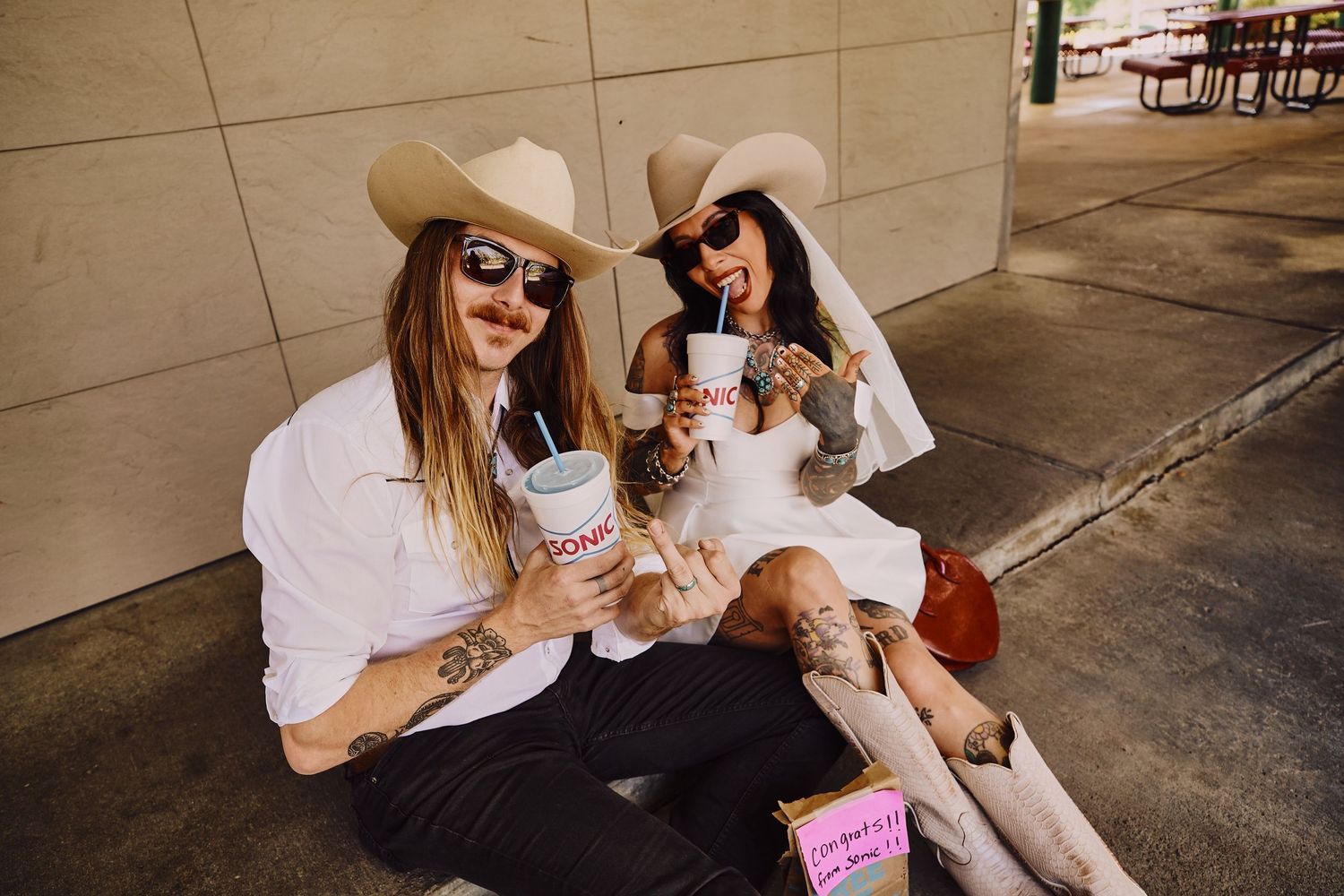 editorial photoshoot of bride and groom in western attire enjoying Sonic drinks and snacks outdoors.