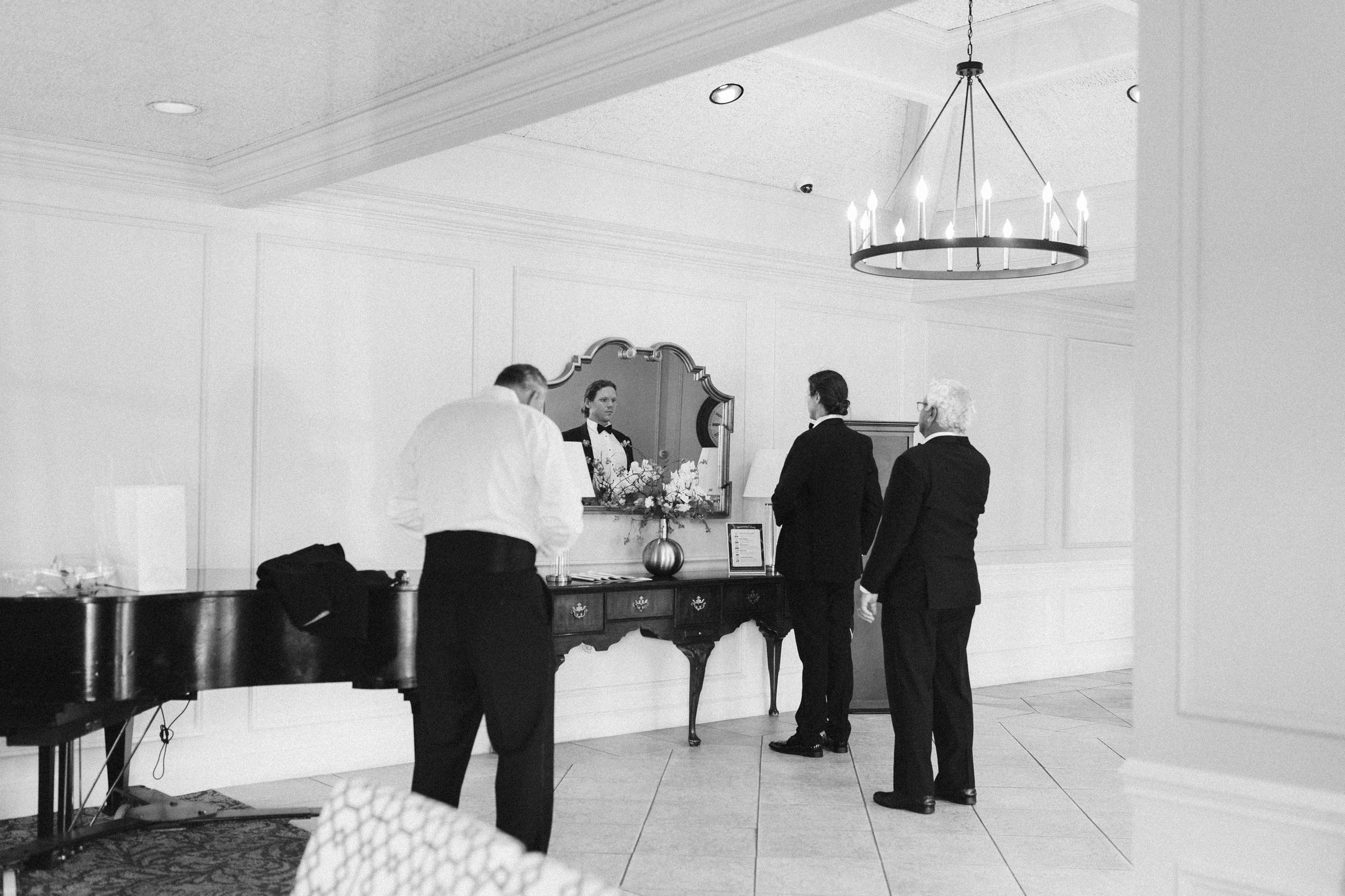 Black and white photo of formal event guests mingling in an elegant venue.