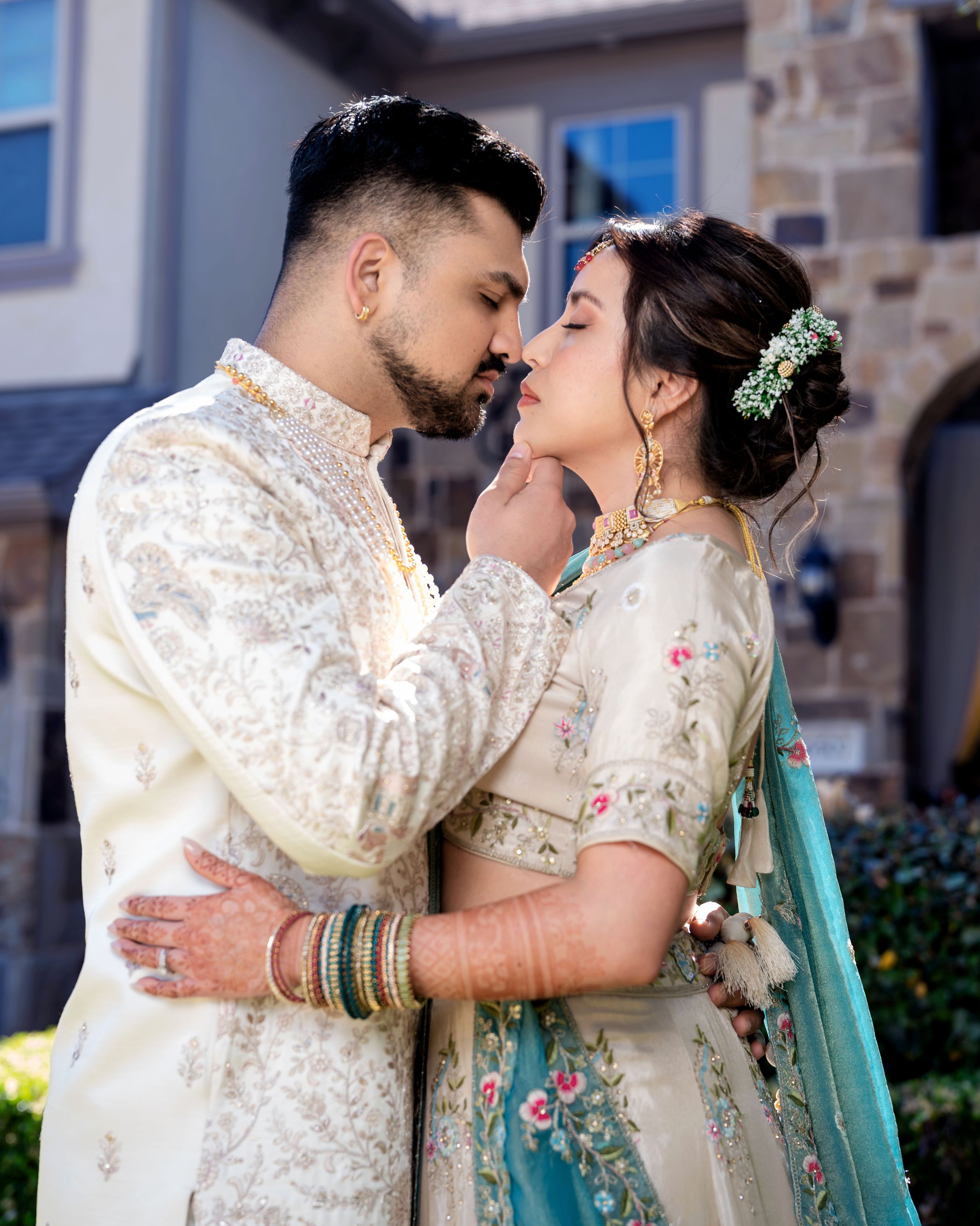 A couple in traditional South Asian wedding attire share an intimate moment during their outdoor photo session.