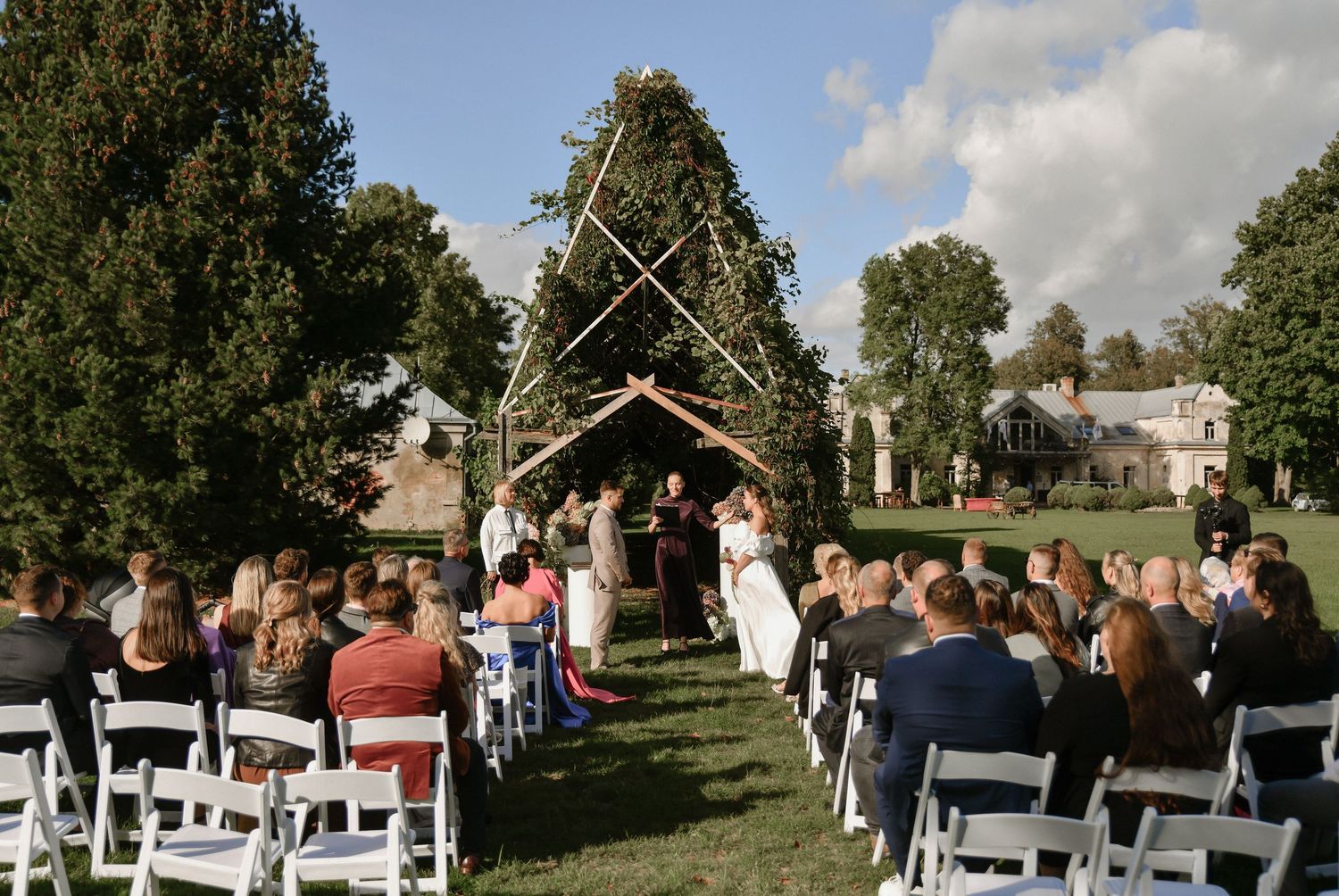 Panoramic sequence of an outdoor wedding ceremony with guests seated in white chairs among trees and greenery.