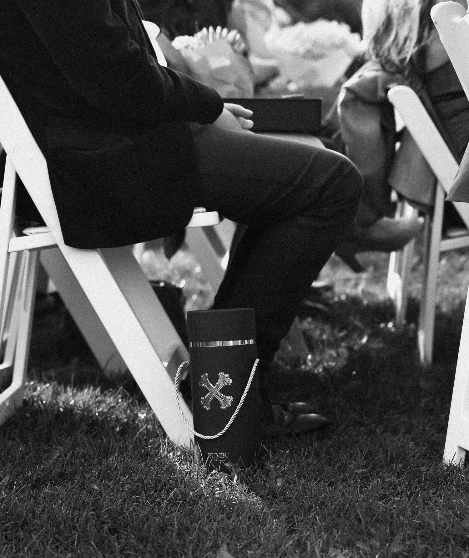 Black and white detail shot of formal shoes with decorative socks at an outdoor wedding ceremony.