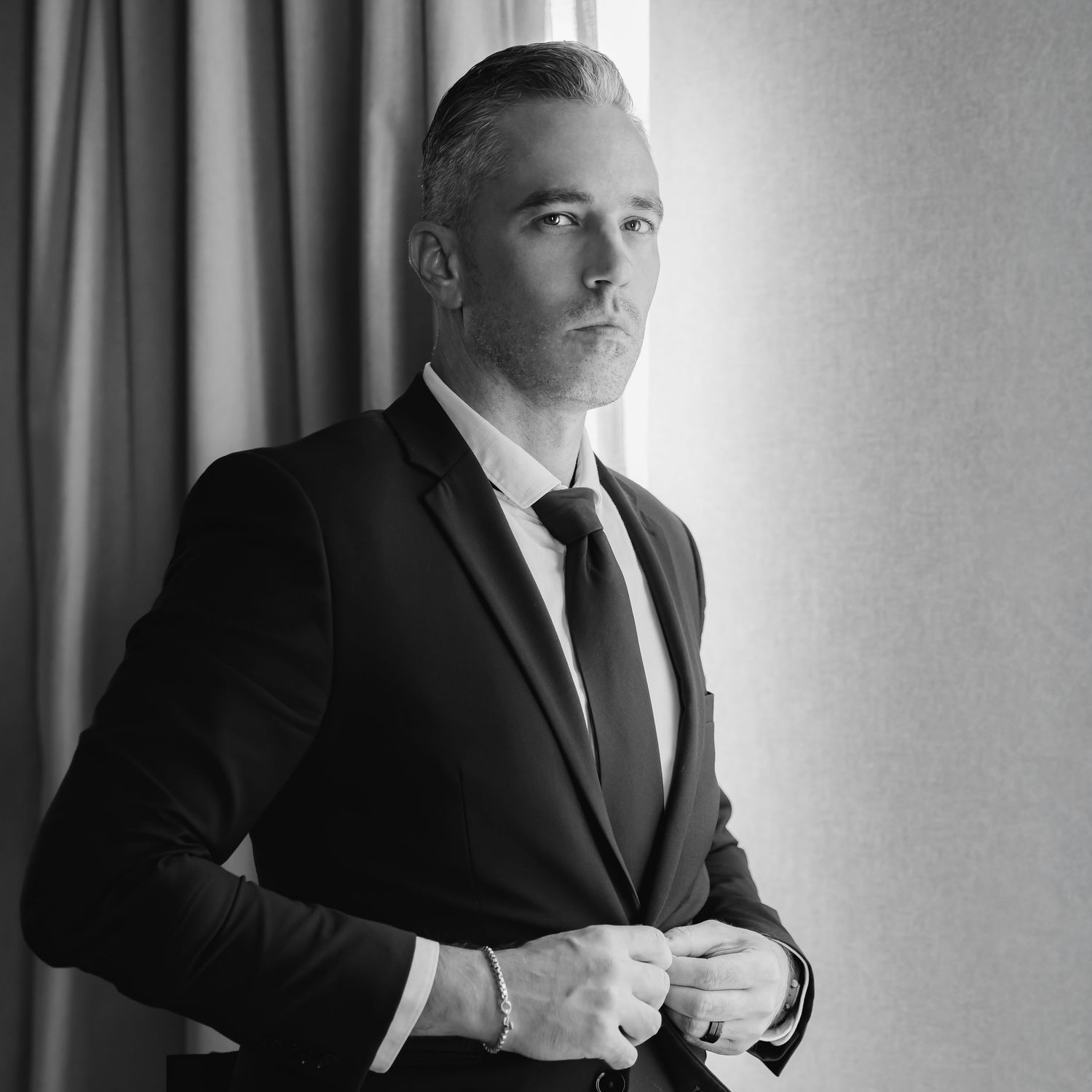 Black and white portrait series showing a person in a suit seated against a light background.