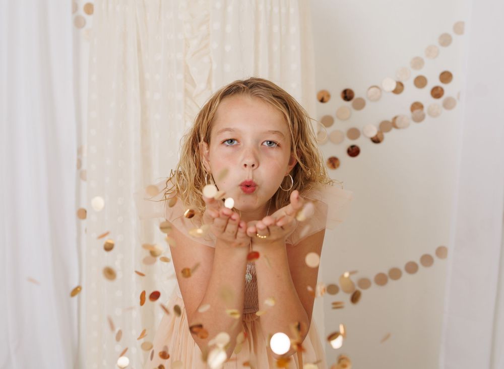 Festive photo setup with floating gold confetti against white backdrop.