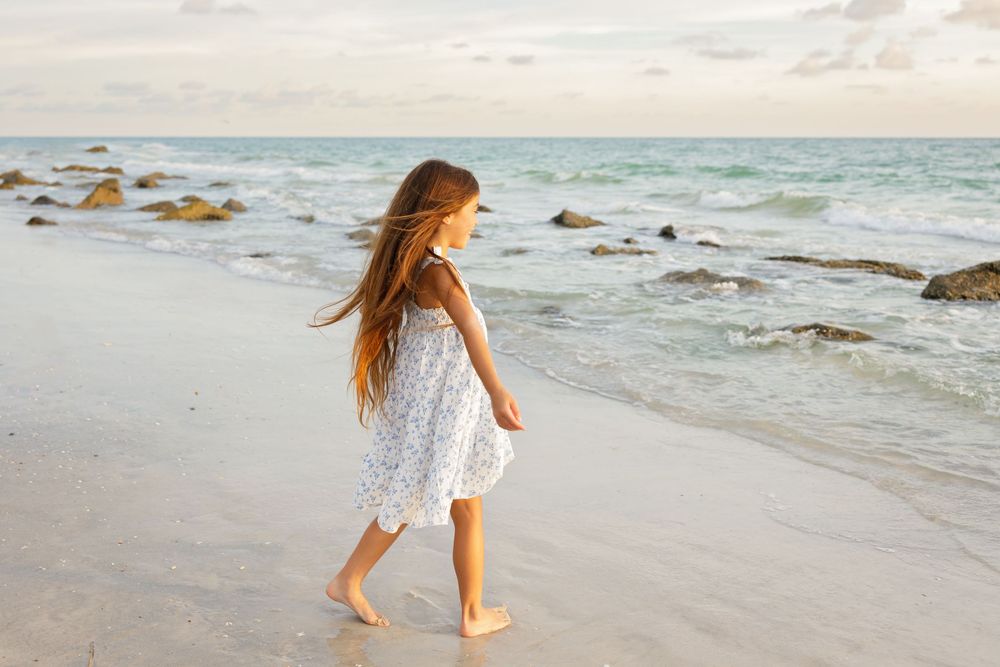 Serene beach scene at sunset with waves crashing against rocky shoreline.