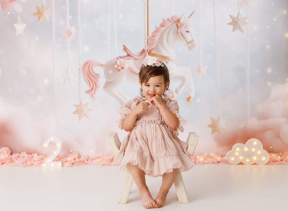 Whimsical unicorn-themed photo setup with pink stars and soft white backdrop.