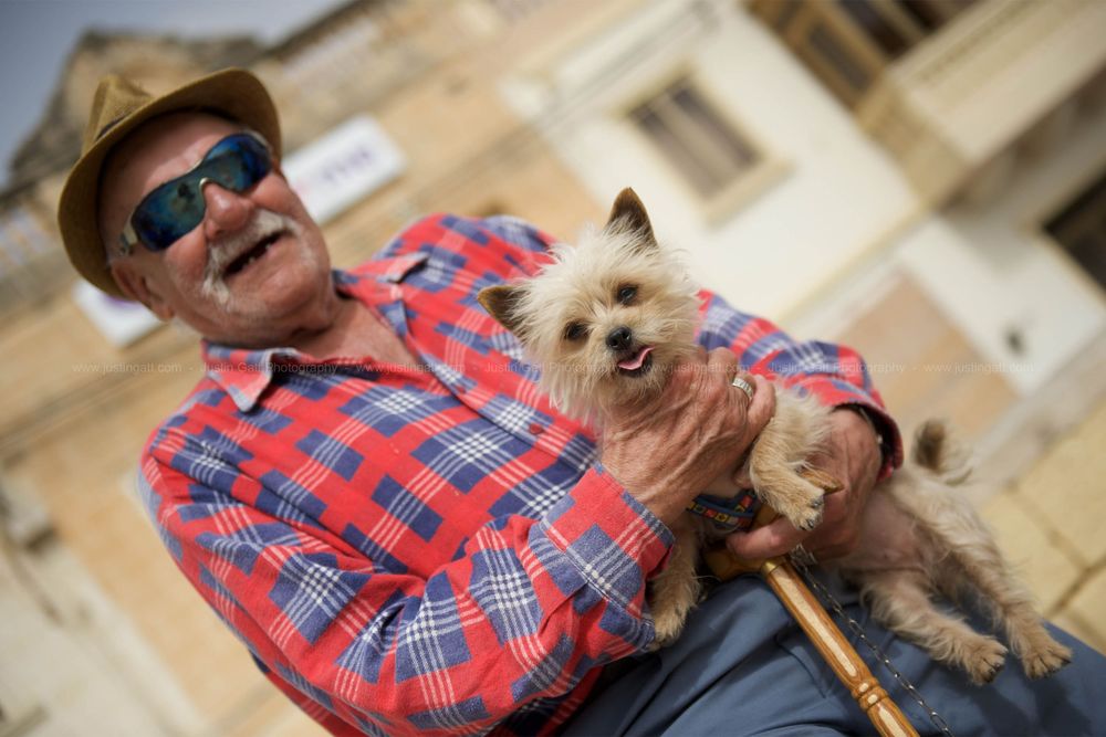 Person in plaid shirt enjoying a sunny day with small dog outdoors.