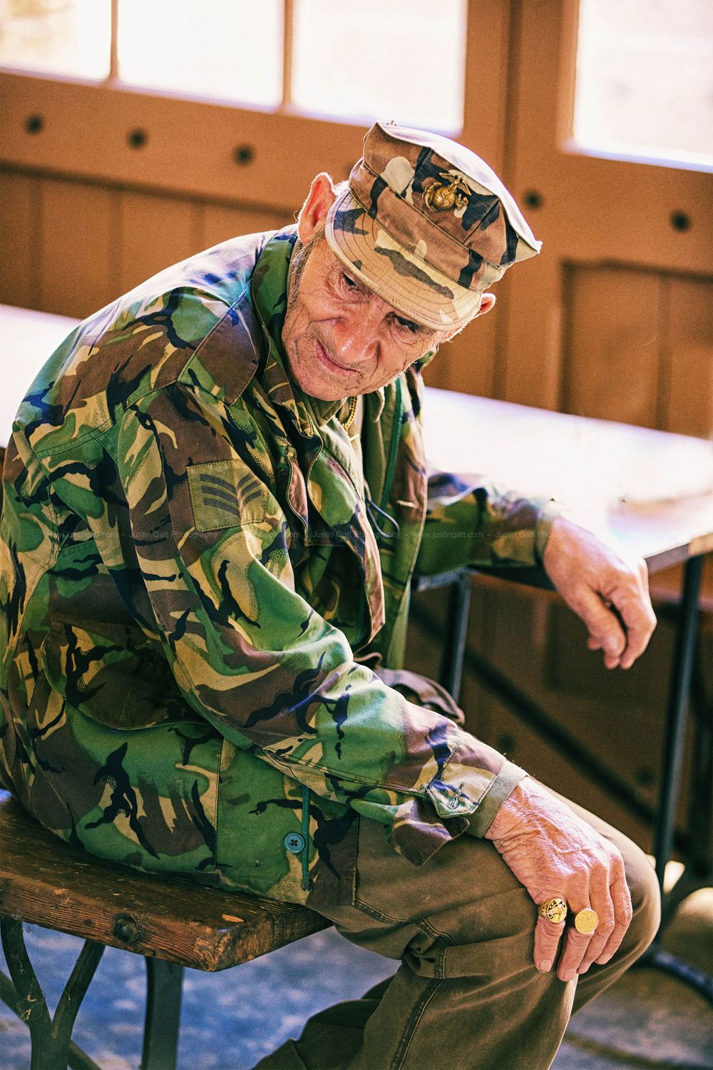Person wearing camouflage military uniform sitting indoors in sequential motion.