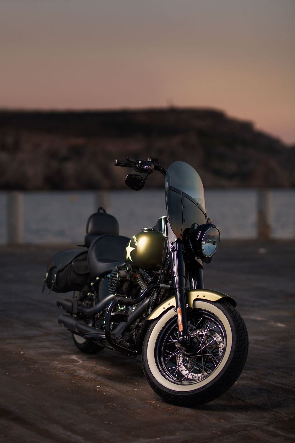 Vintage motorcycles displayed at dusk with mountains in the background.