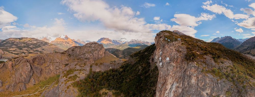 A panoramic mountain landscape with snow-capped peaks and rugged terrain stretches across multiple connected images.