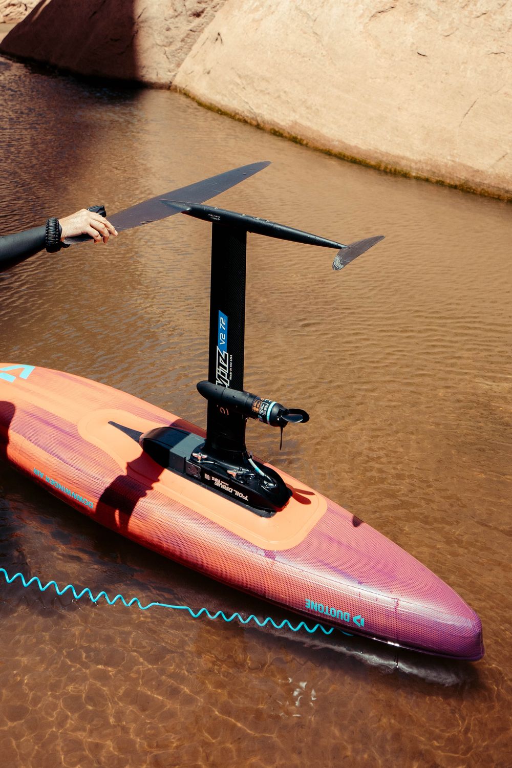 Close-up sequence of hydrofoil wing attachment being mounted on a pink surfboard in muddy water.