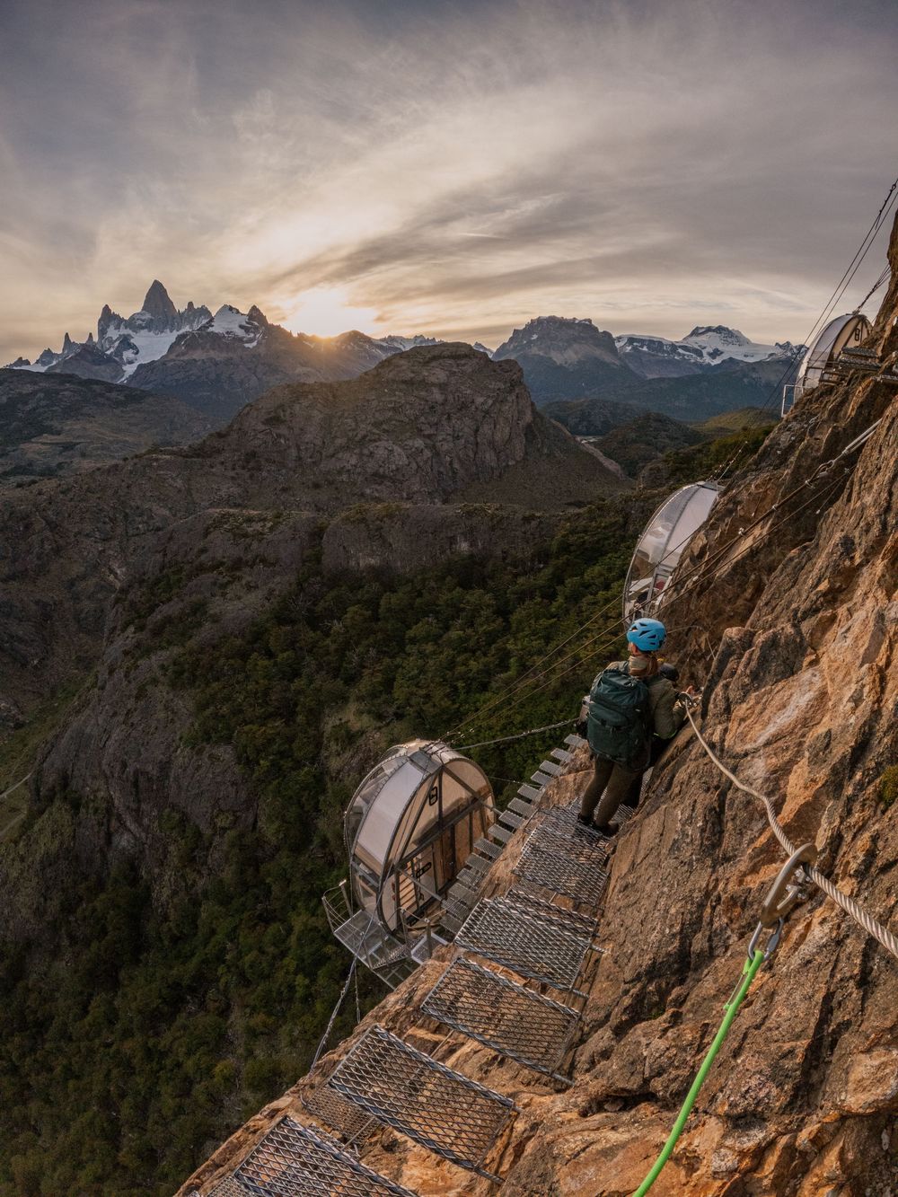 Dramatic mountain landscape with winding wooden boardwalk trail leading to rugged peaks during sunset in Patagonia.