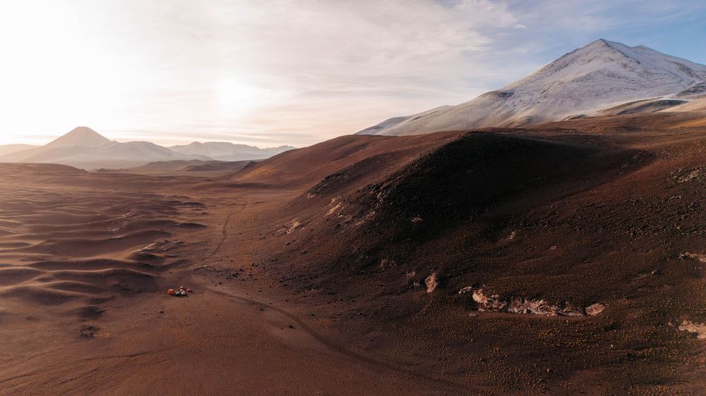 Panoramic mountain landscape with rugged peaks and barren brown terrain stretching across a vast wilderness area.
