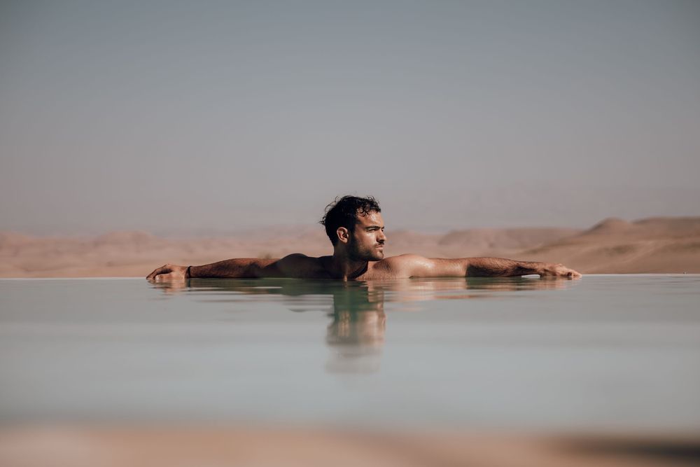 Person floating in calm pink salt lake water at sunset creating a serene and peaceful scene.