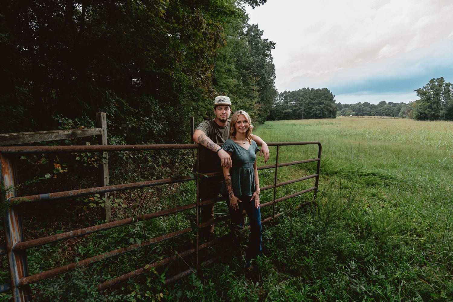 A series of people leaning against rustic wooden fences along a scenic countryside path with green rolling hills.