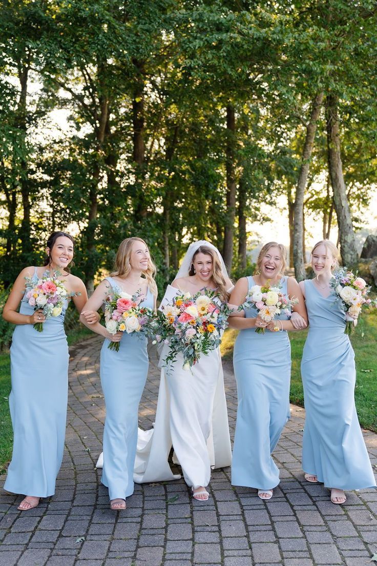 Bride and four bridesmaids in light blue gowns walking outdoors with bouquets.