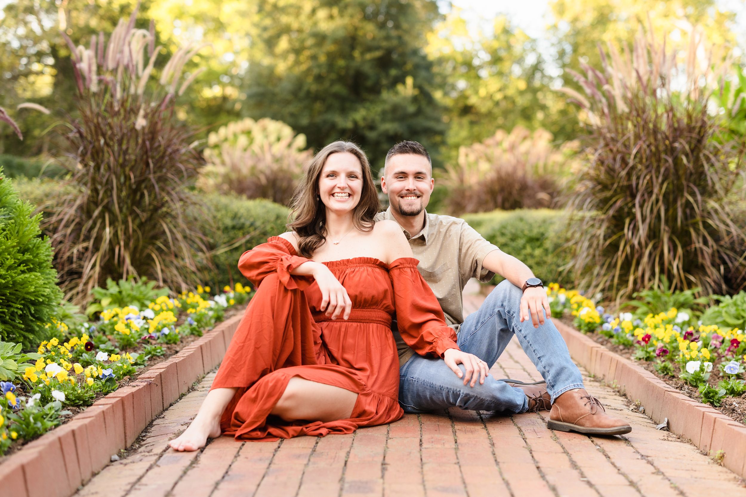 Couple relaxing on brick pathway surrounded by colorful garden flowers.