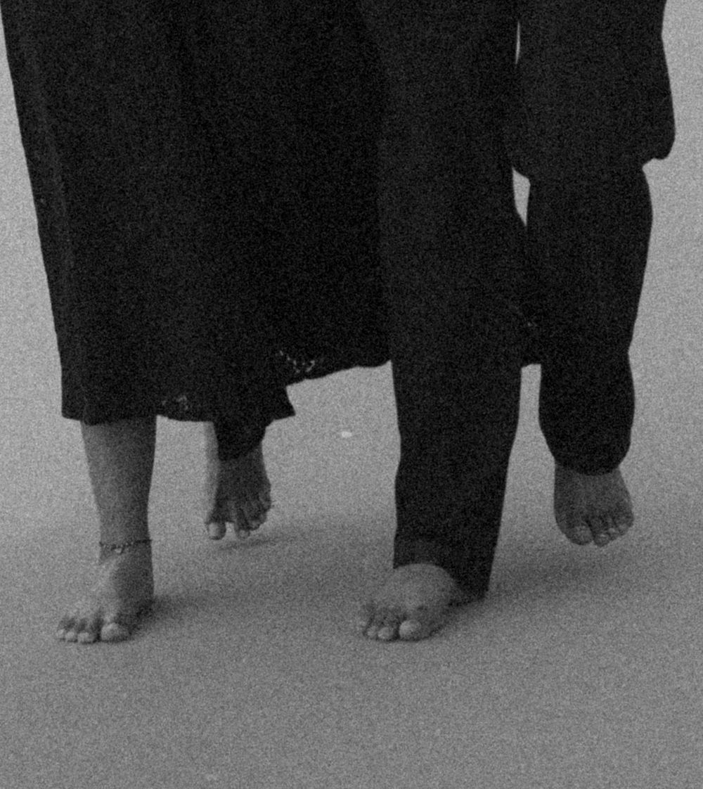 Black and white artistic photograph showing a row of bare feet against a light background.
