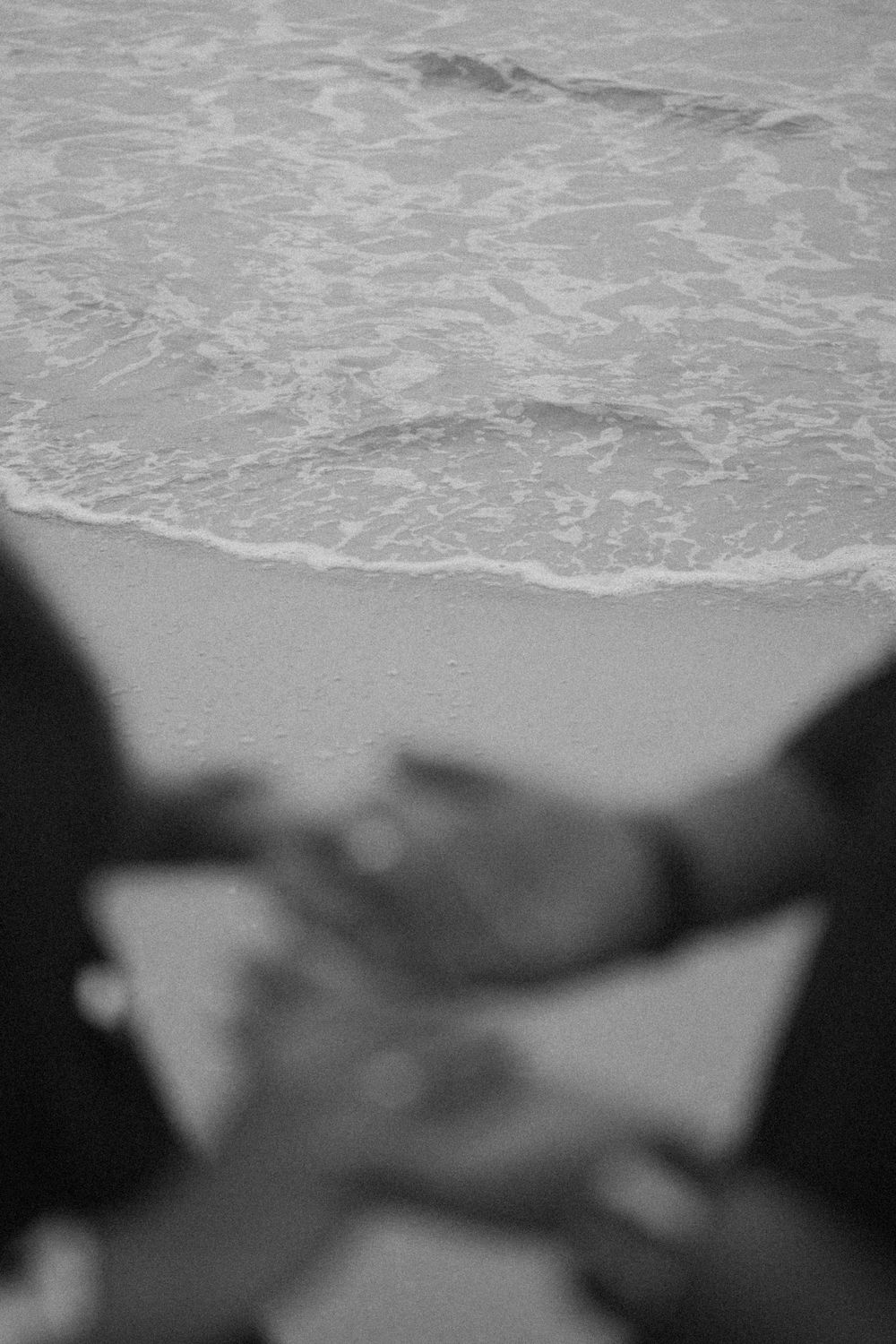 Aerial view of ocean waves breaking on a sandy beach in black and white.