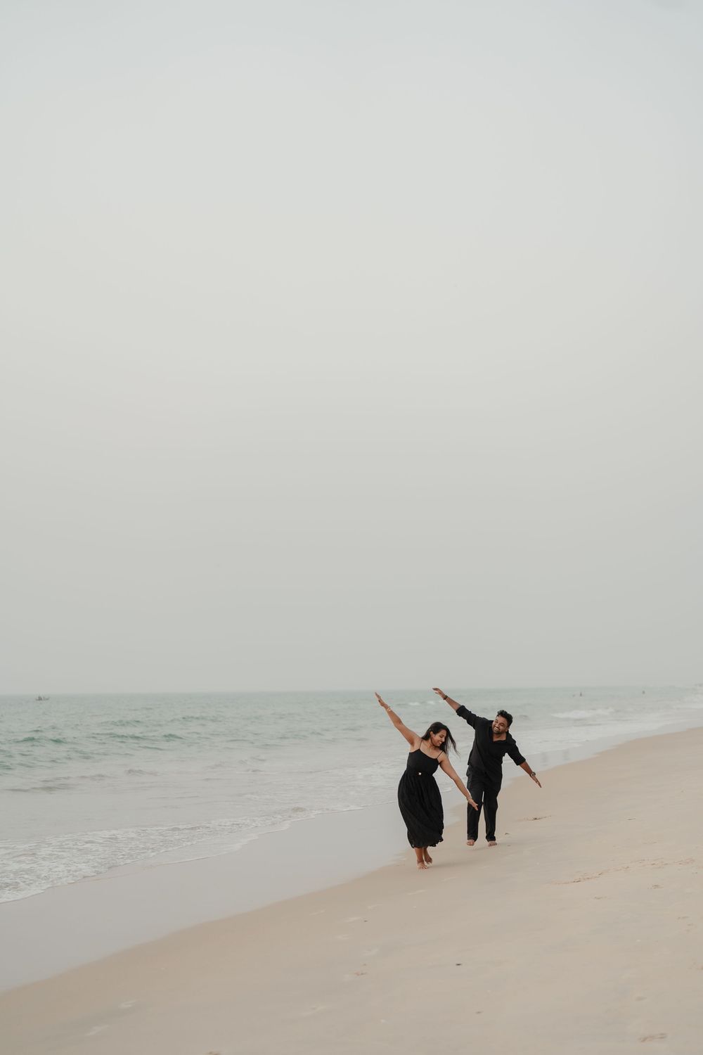 People walking and playing on a foggy beach shoreline with soft muted tones and minimalist aesthetic.