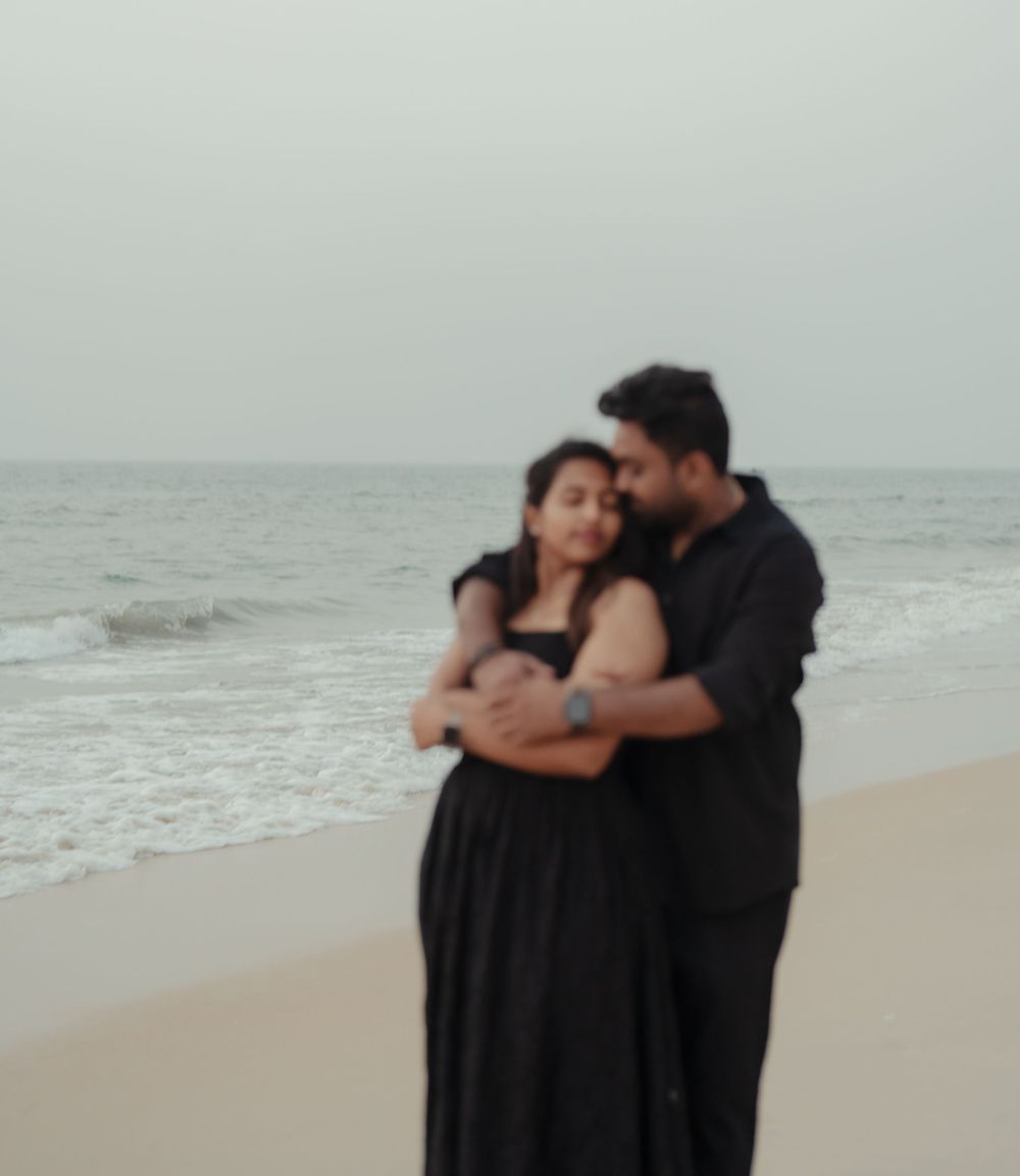 Couple embracing tenderly on a misty beach with soft overcast lighting.