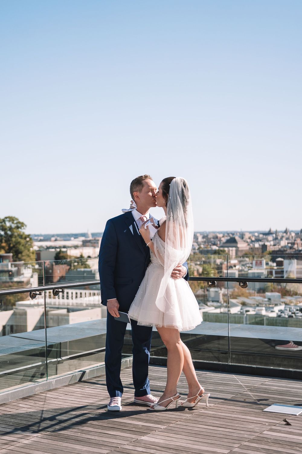Romantic rooftop photoshoot with a couple enjoying city views from a wooden deck.