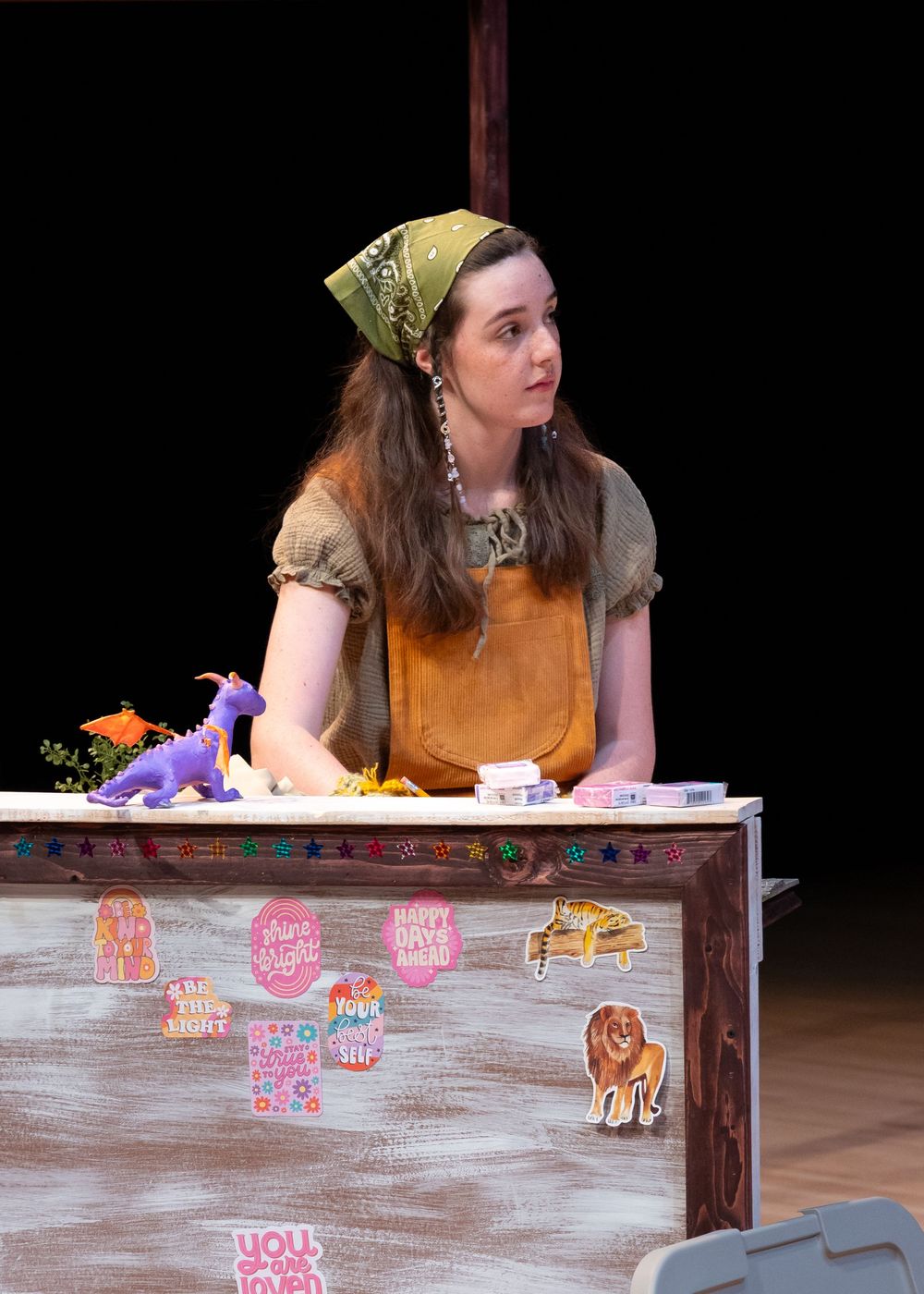 Theater performance scene with actor in yellow costume interacting with props on stage.