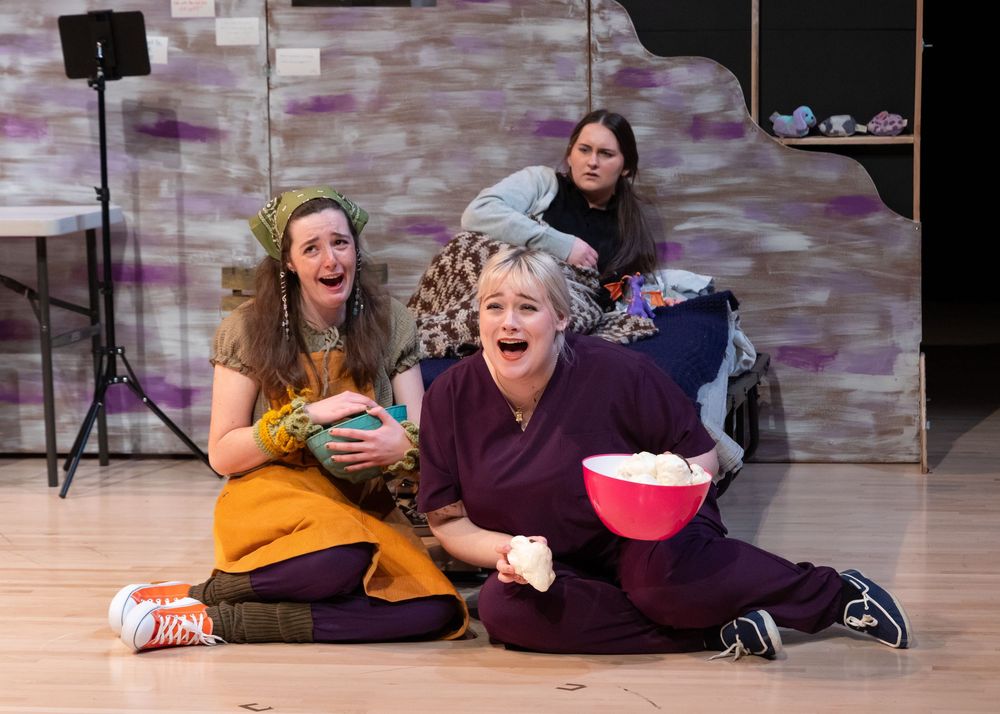 Two performers in casual clothes acting in theatrical scene on stage.