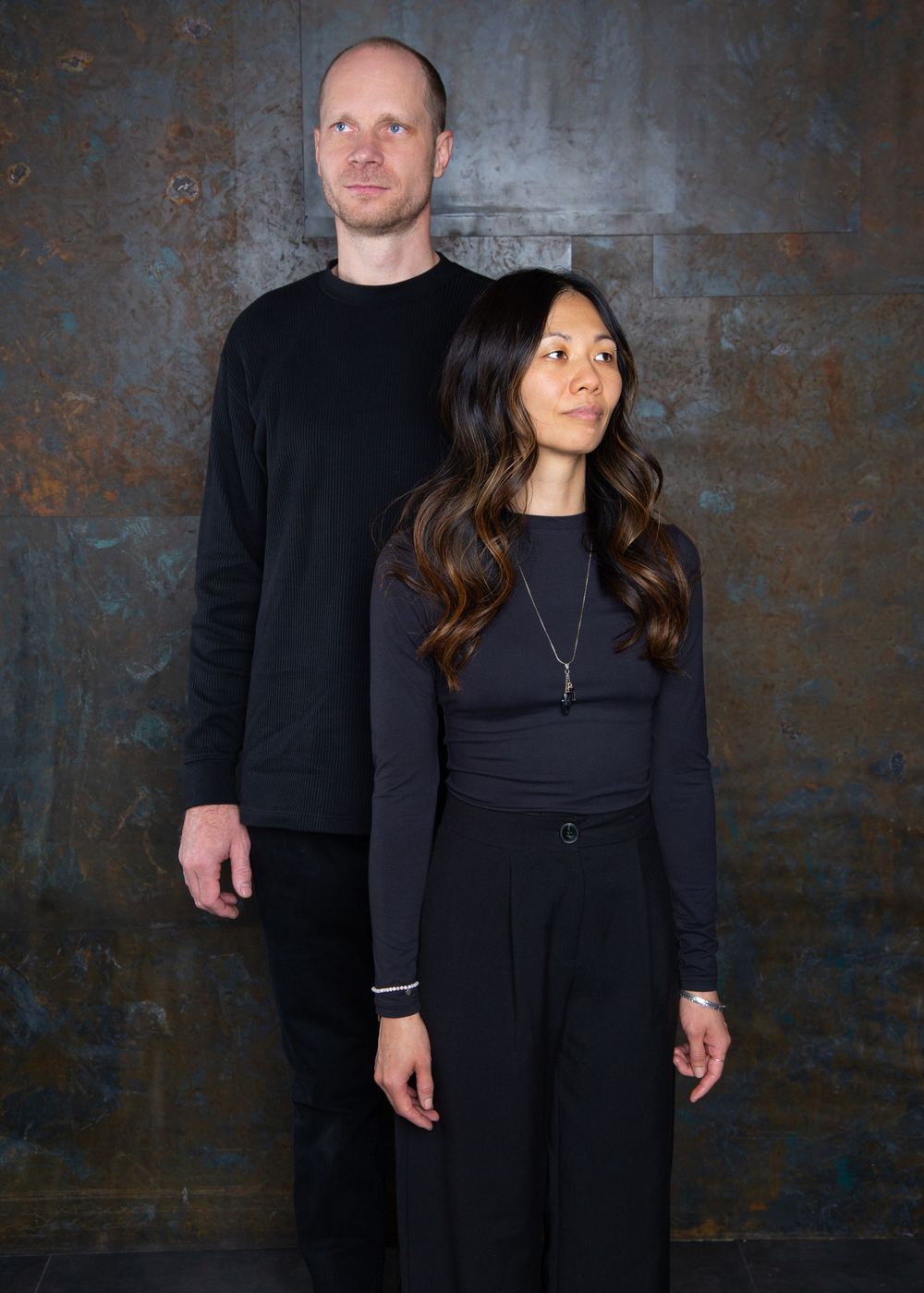 Artistic portrait series of couple in black outfits against industrial metal background.