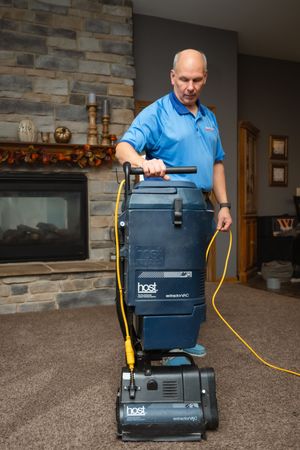 Professional carpet cleaning service in progress with a Host dry extraction vacuum system in a residential living room.