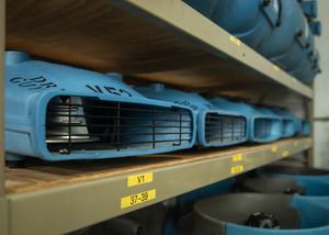 Organized rows of blue medical scrubs hang neatly on shelving units in a storage facility.