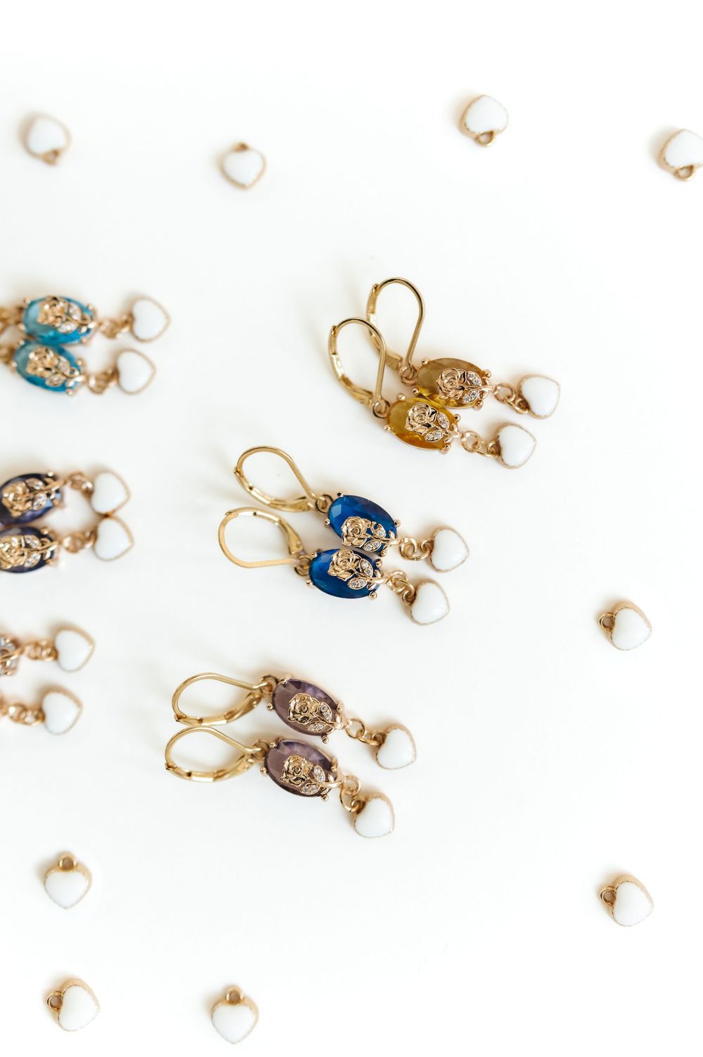 Collection of gold dangle earrings with pearls displayed in a linear arrangement.