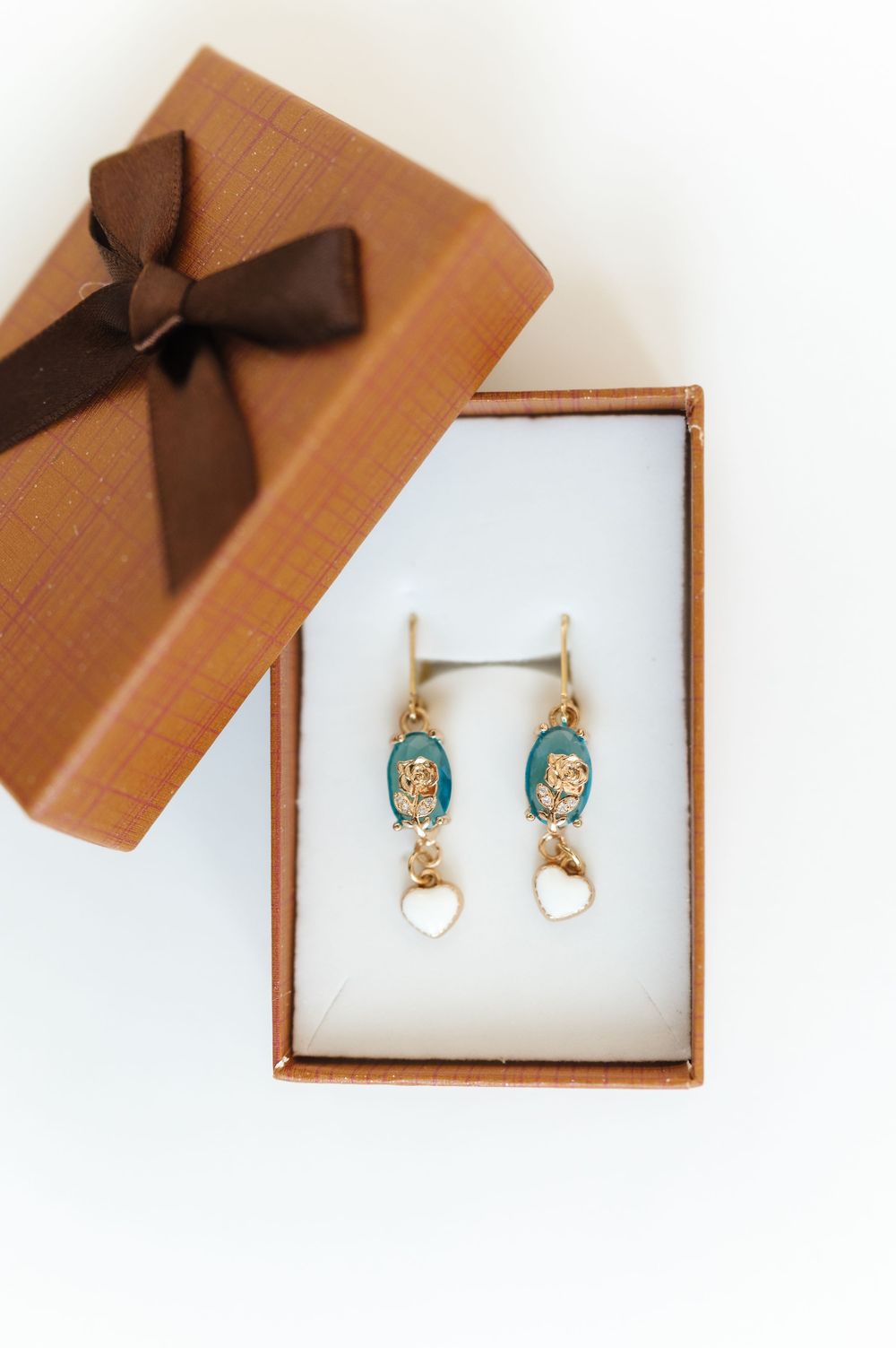 Brown gift boxes with bows displaying elegant turquoise and gold earrings.