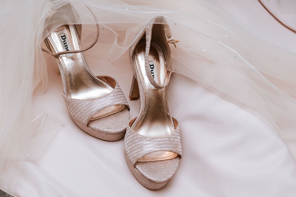 Elegant silver metallic high heel sandals with straps photographed on white fabric in multiple angles.