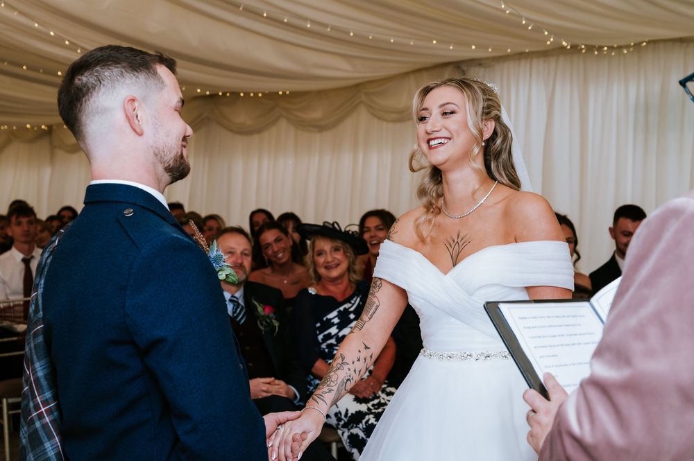 Guests dance and celebrate at an elegant indoor wedding reception under twinkling string lights.