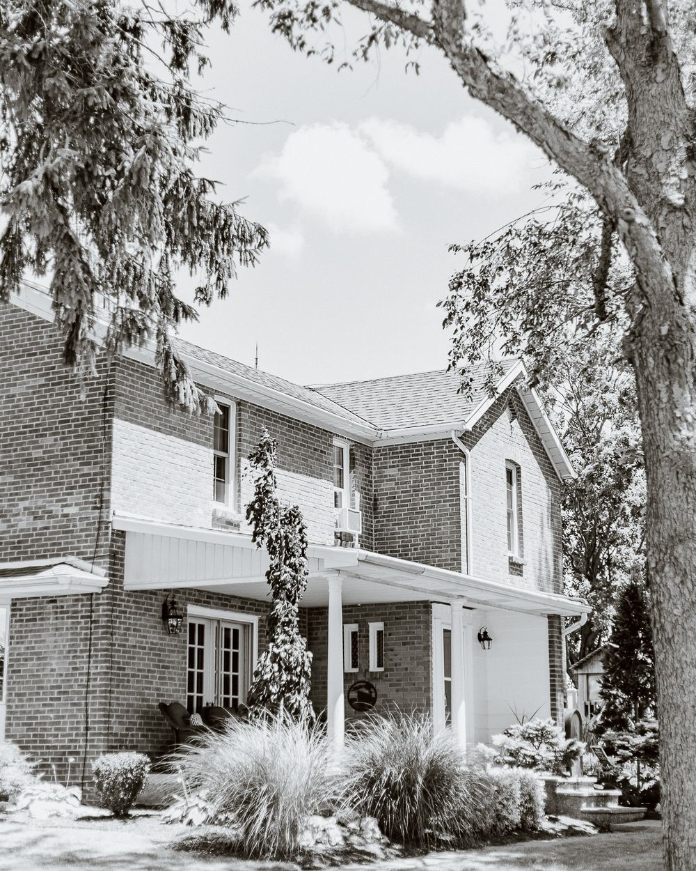 Classic two-story brick house with white trim and landscaped garden.