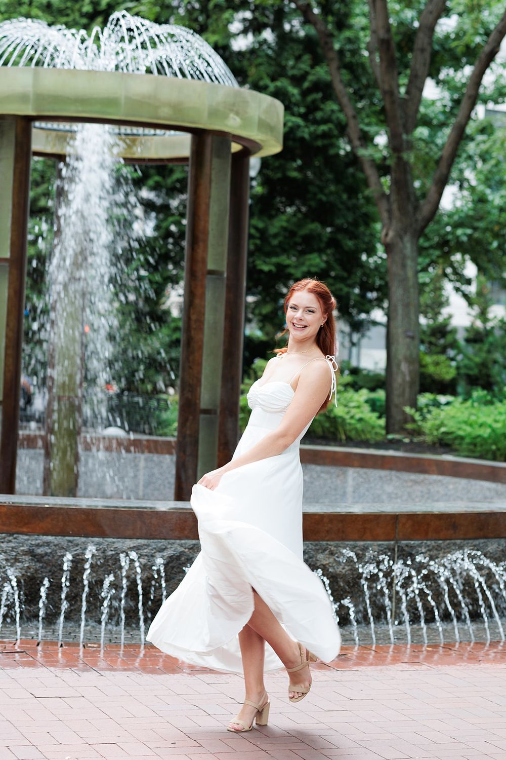 A sequence of photos showing someone in a white dress twirling and dancing by a fountain in a garden setting.